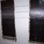 Carbon fiber strips applied to a basement wall for foundation crack repair, illustrating StablWall's method for enhancing structural stability.