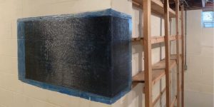 Carbon fiber straps installed on a basement wall to reinforce and stabilize foundation cracks.